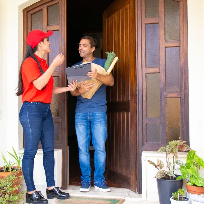 Latin postwoman holding clipboard and delivering order